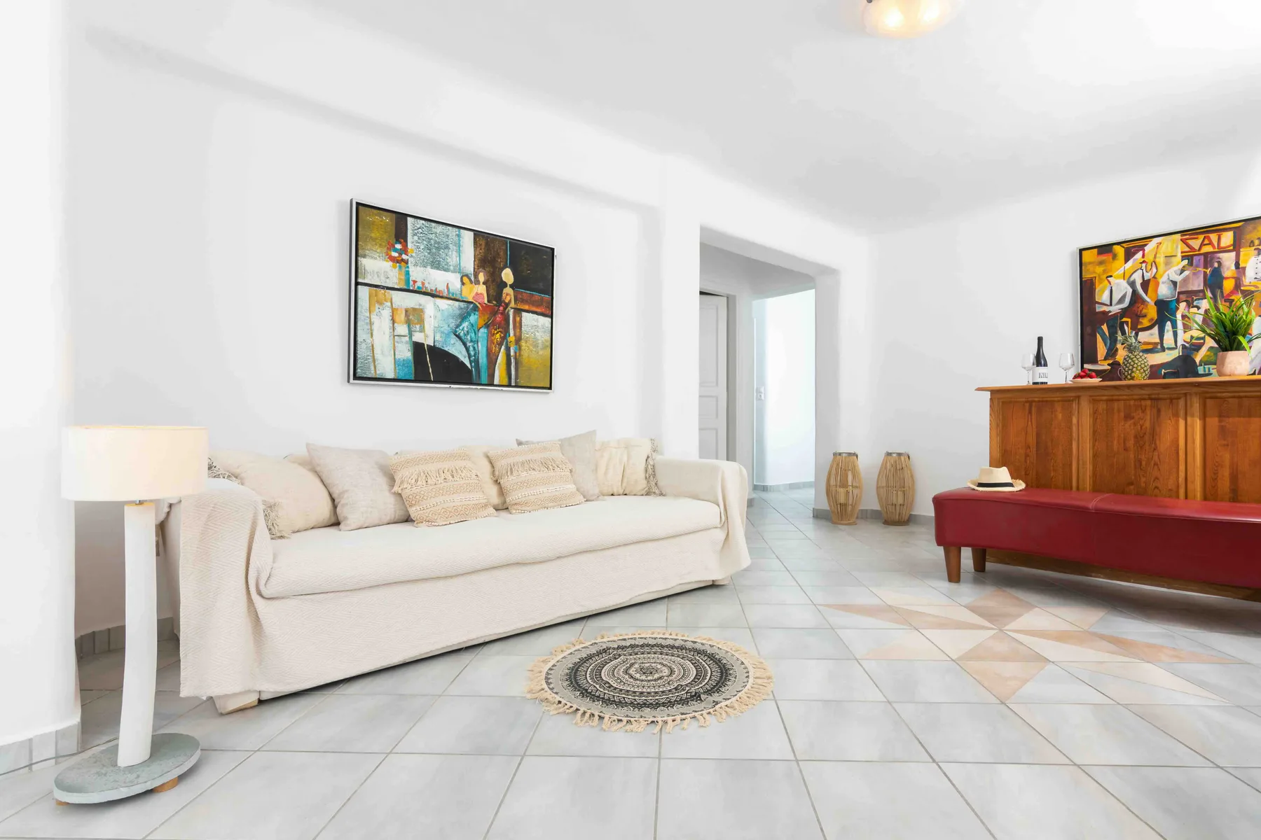 A bright living room with seating, colorful wall art, and a wooden cabinet.