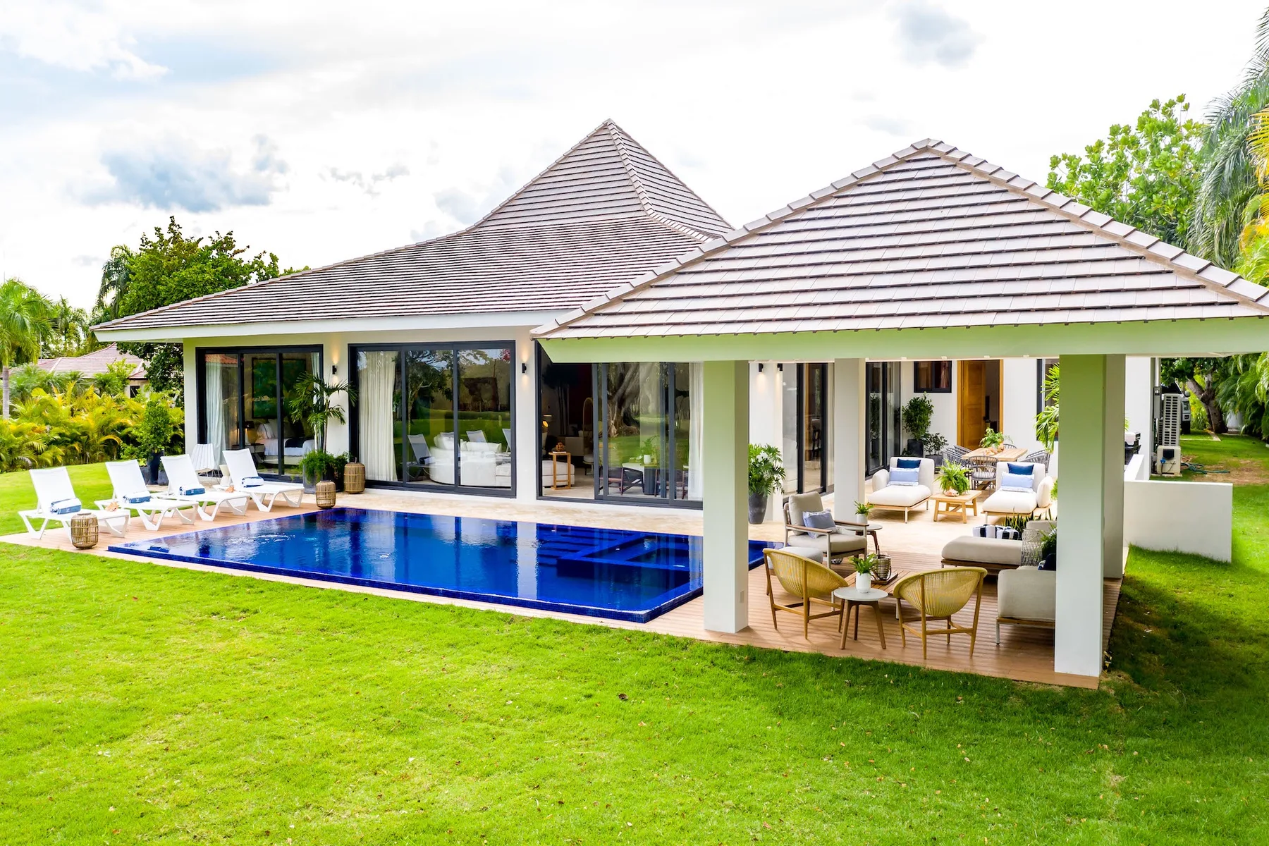 Una casa moderna da a una piscina azul y un patio cubierto.