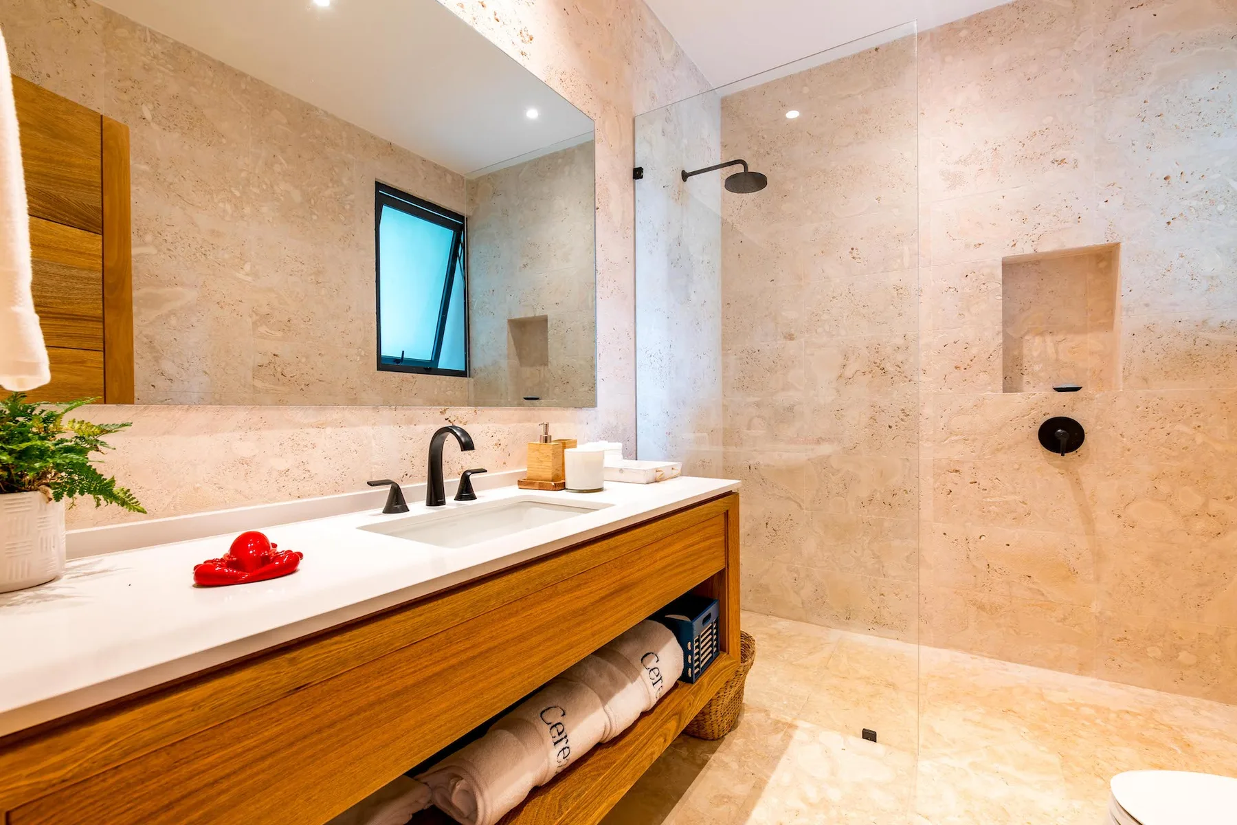 Un baño con un lavabo largo y una zona de ducha abierta.