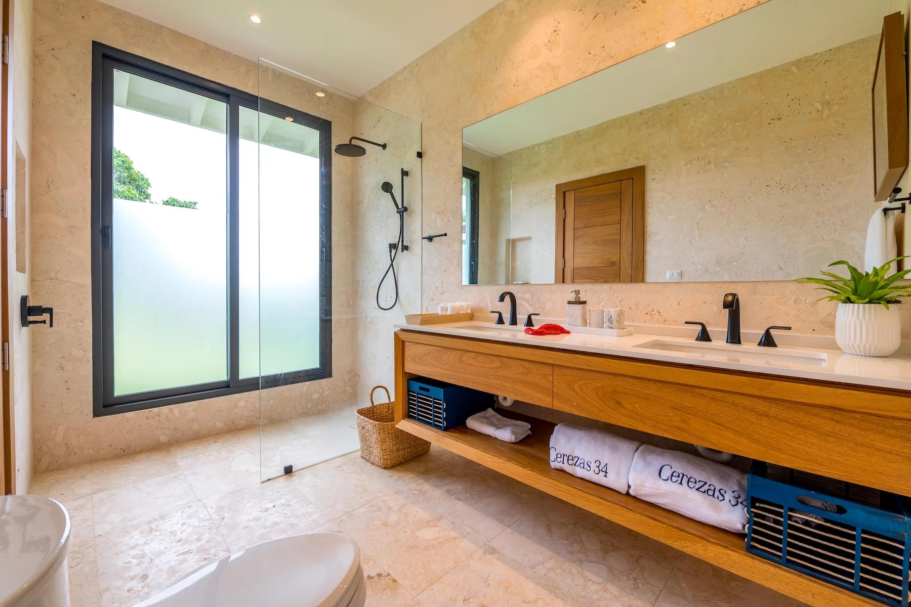 Un baño luminoso con una ventana grande, ducha y tocador largo.