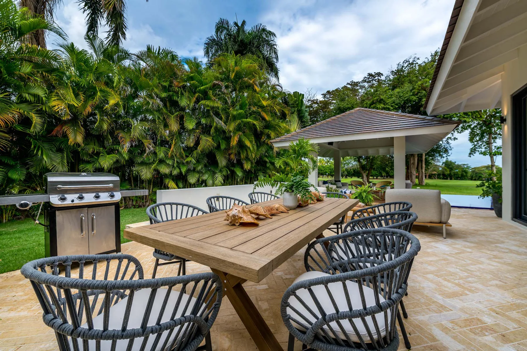 Un patio comedor al aire libre con una mesa de madera y vegetación.
