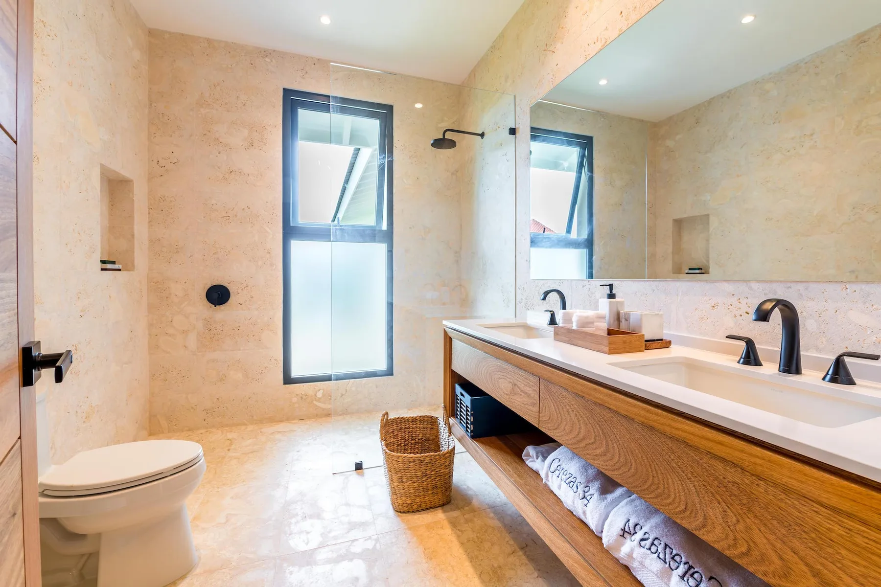 Un baño luminoso con un tocador largo, lavabo y ventana.
