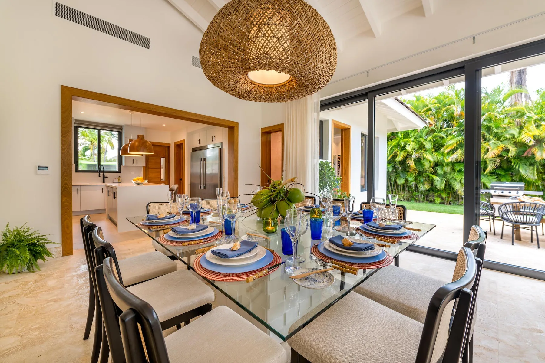 Comedor con una mesa de vidrio junto a grandes puertas corredizas de cristal.