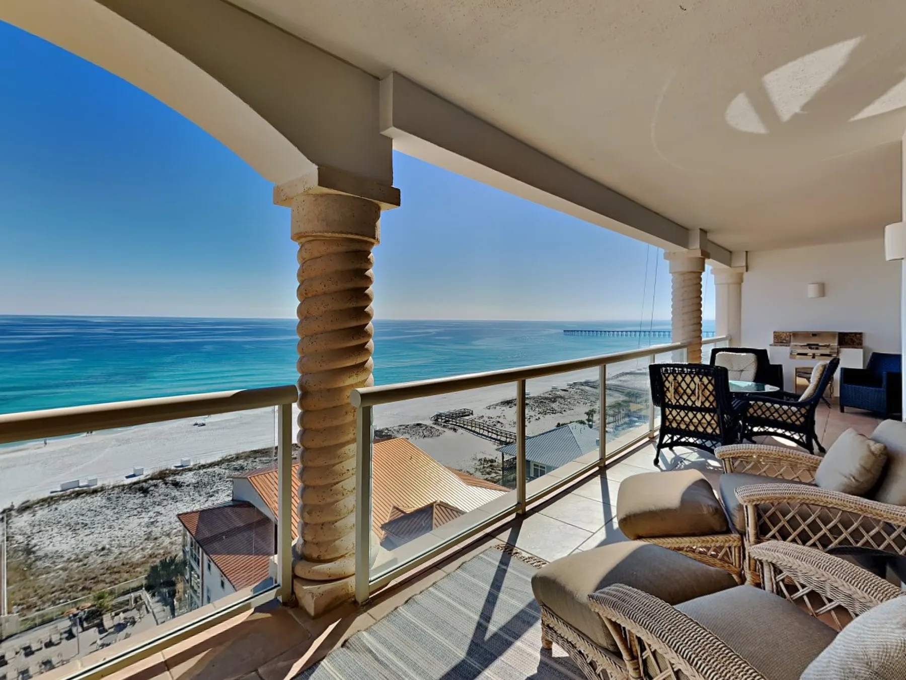 A seaside balcony with lounge seating overlooks the beach and ocean.