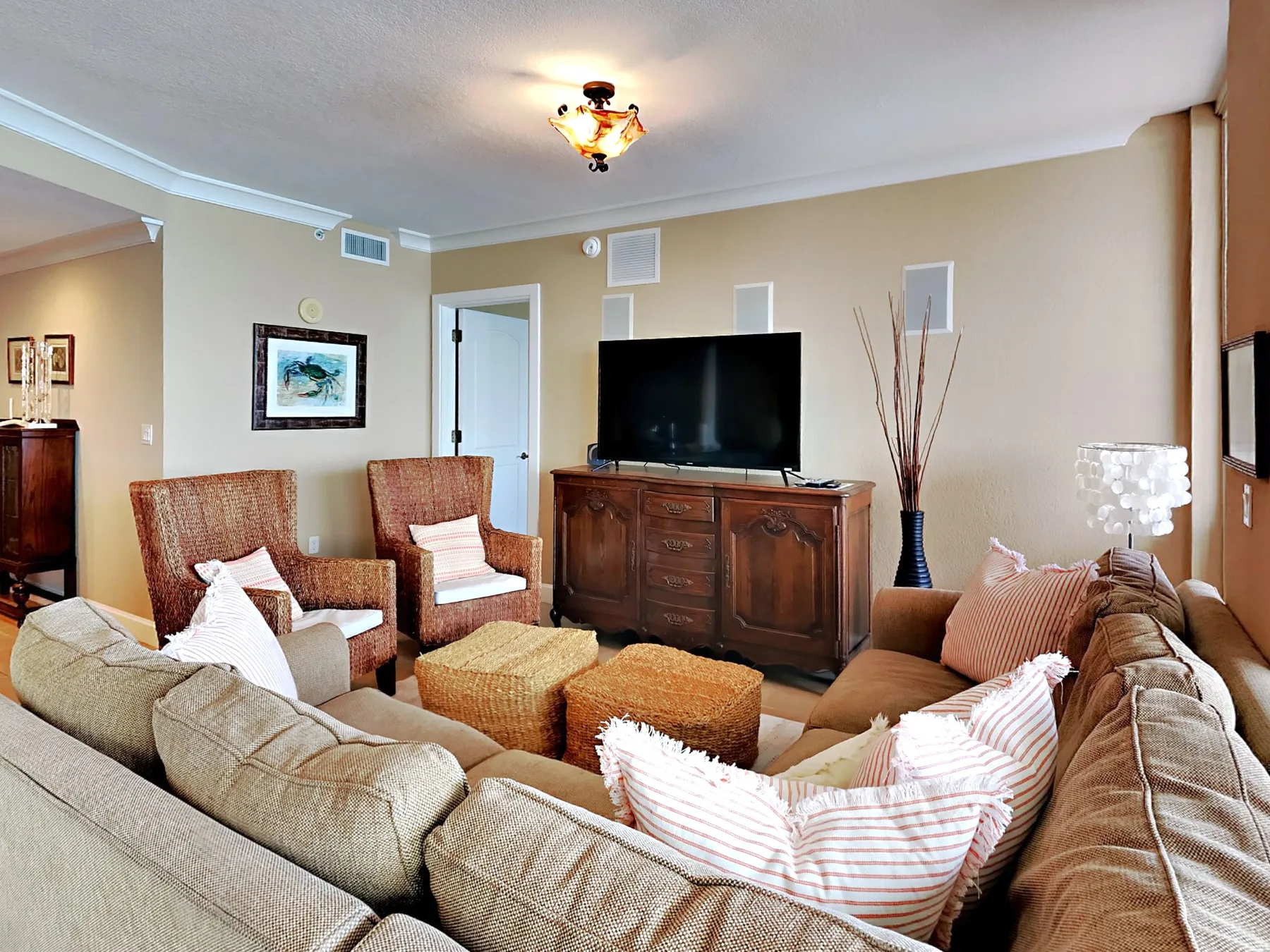 A living room with a television, seating, and woven ottomans.