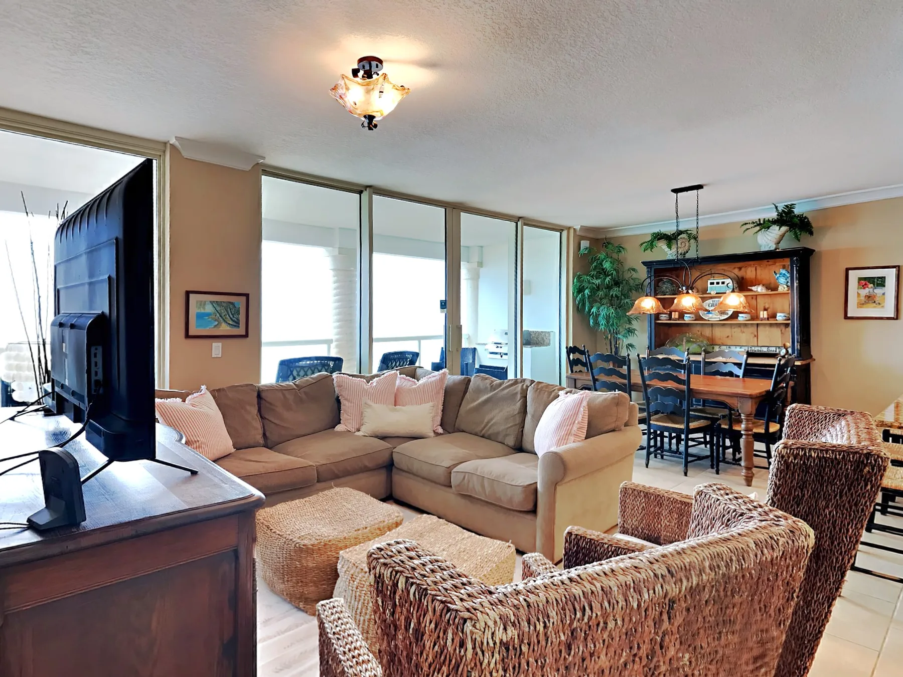 A living room with a sectional seating area, wicker chairs, and a dining table.