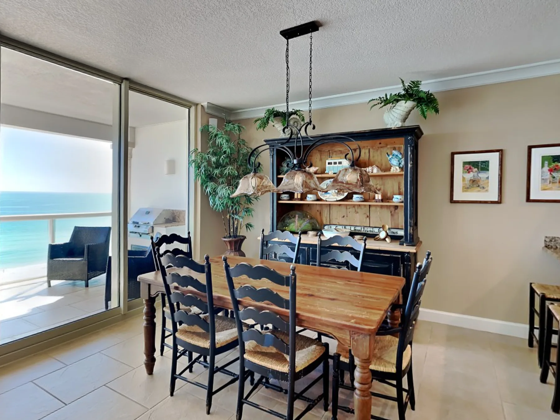 A dining area with a wooden table and chairs beside large windows overlooking the water.