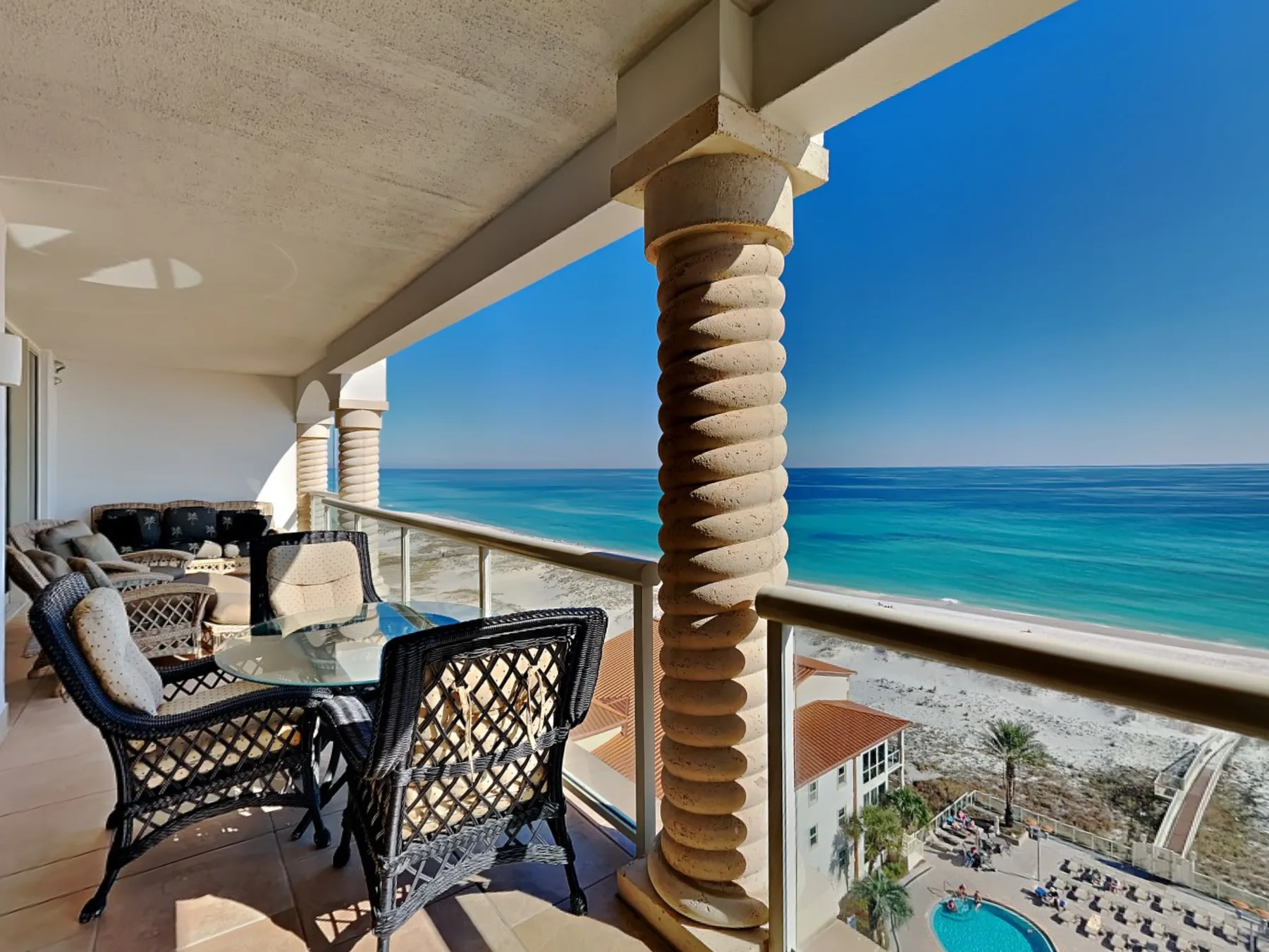 A seaside balcony with outdoor seating overlooks the ocean.