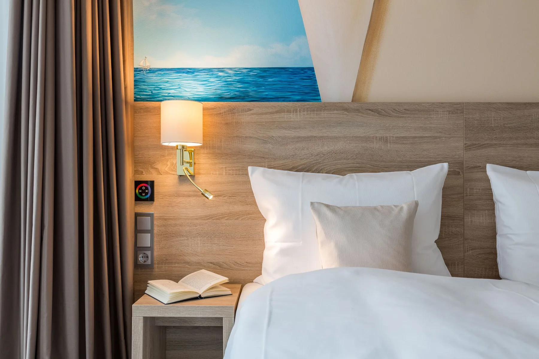Dormitorio con una cama, una mesita de noche y decoración mural de temática marítima.