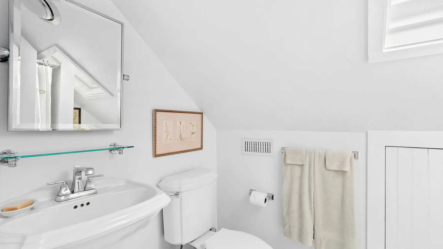 Un baño luminoso con lavabo, inodoro y toallas colgadas en la pared.