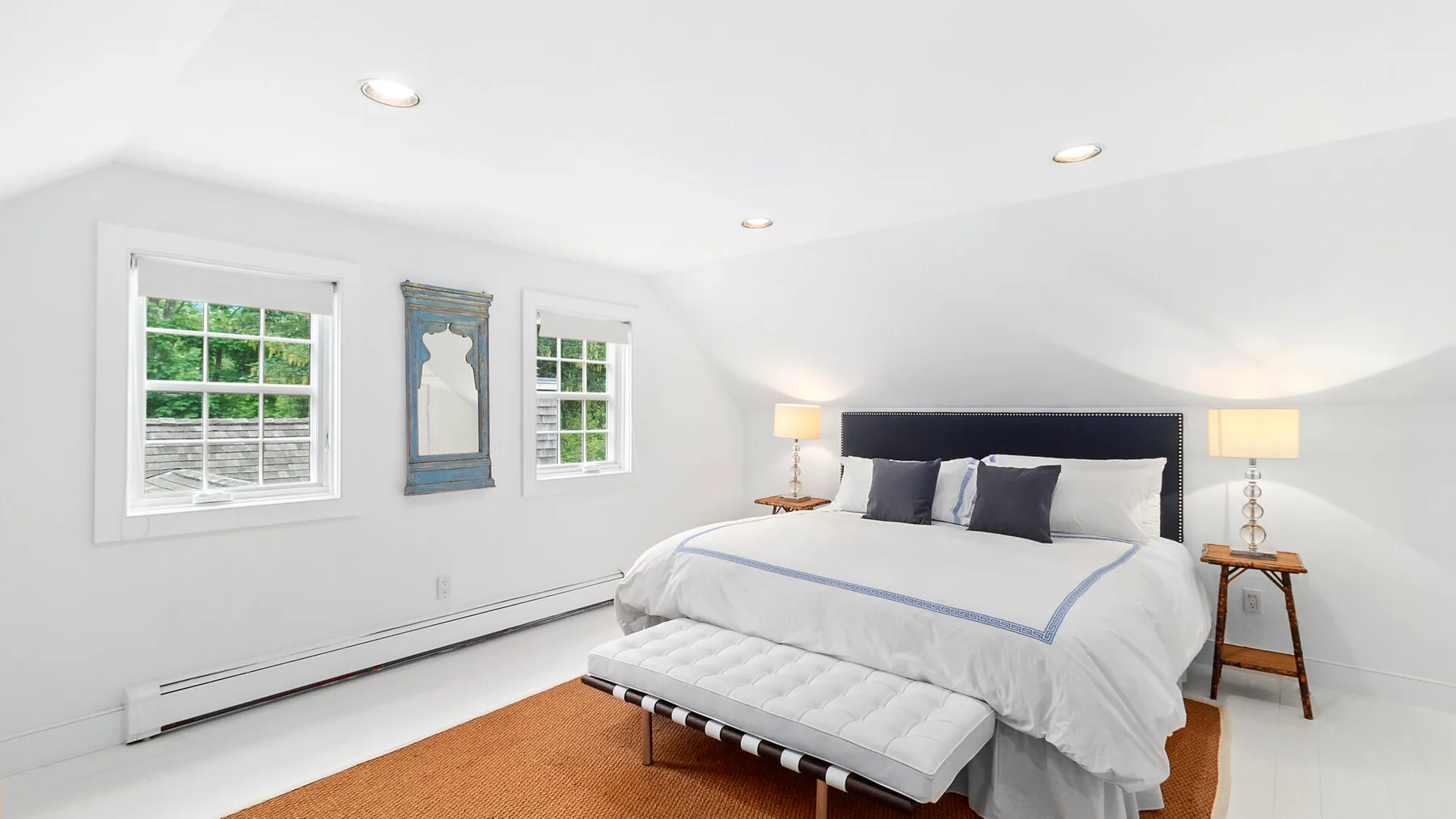 Un dormitorio luminoso con una cama bien hecha y dos ventanas.