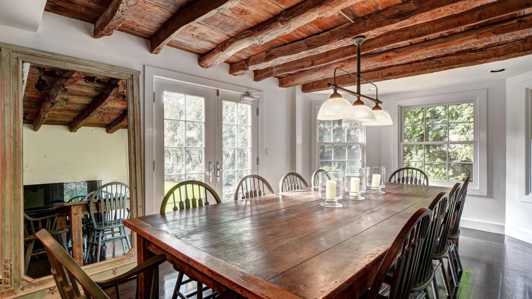 Un comedor con una larga mesa de madera bajo vigas expuestas.