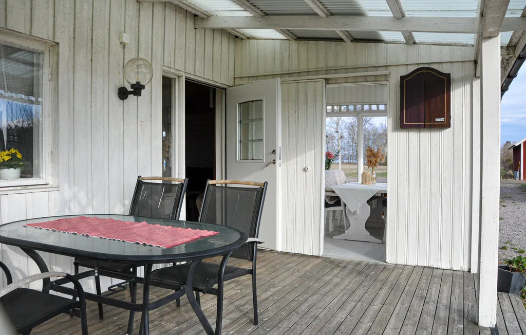 A covered outdoor seating area with a table beside open doors.