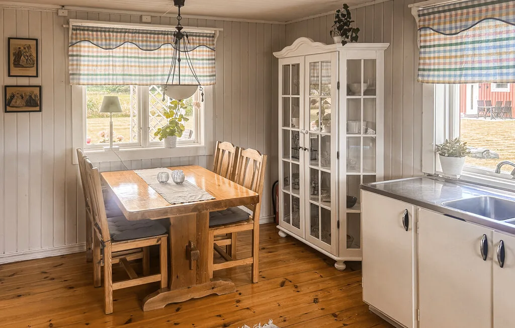 A dining area with a wooden table beside a kitchen counter and windows.