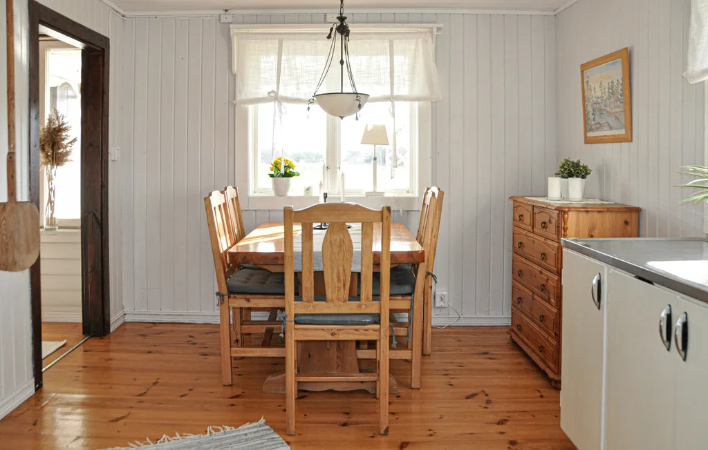 A dining area with a wooden table and chairs beneath a window.