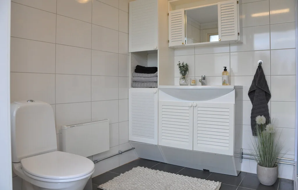 A tiled bathroom with a toilet, vanity, and mirror.