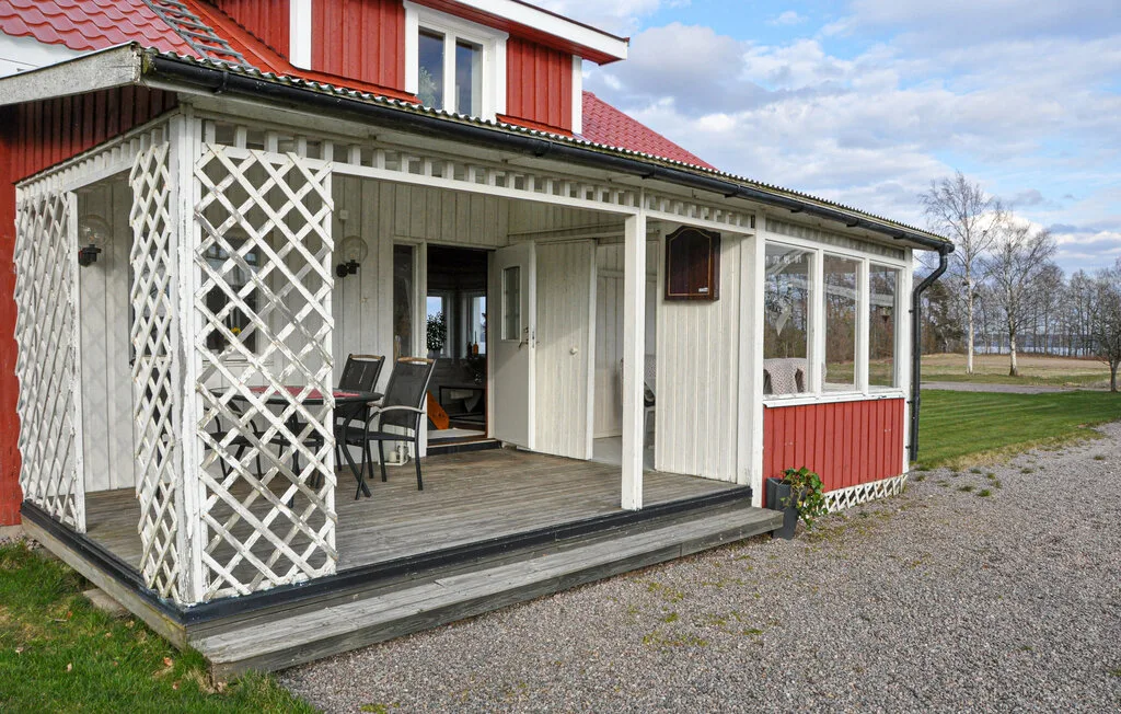 A covered porch with outdoor seating sits beside a white and red house.