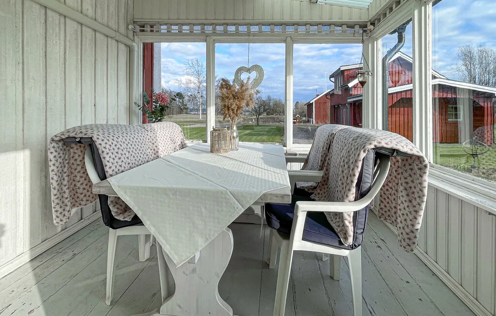 A glass-enclosed dining area has a table with a white cloth and surrounding seating.