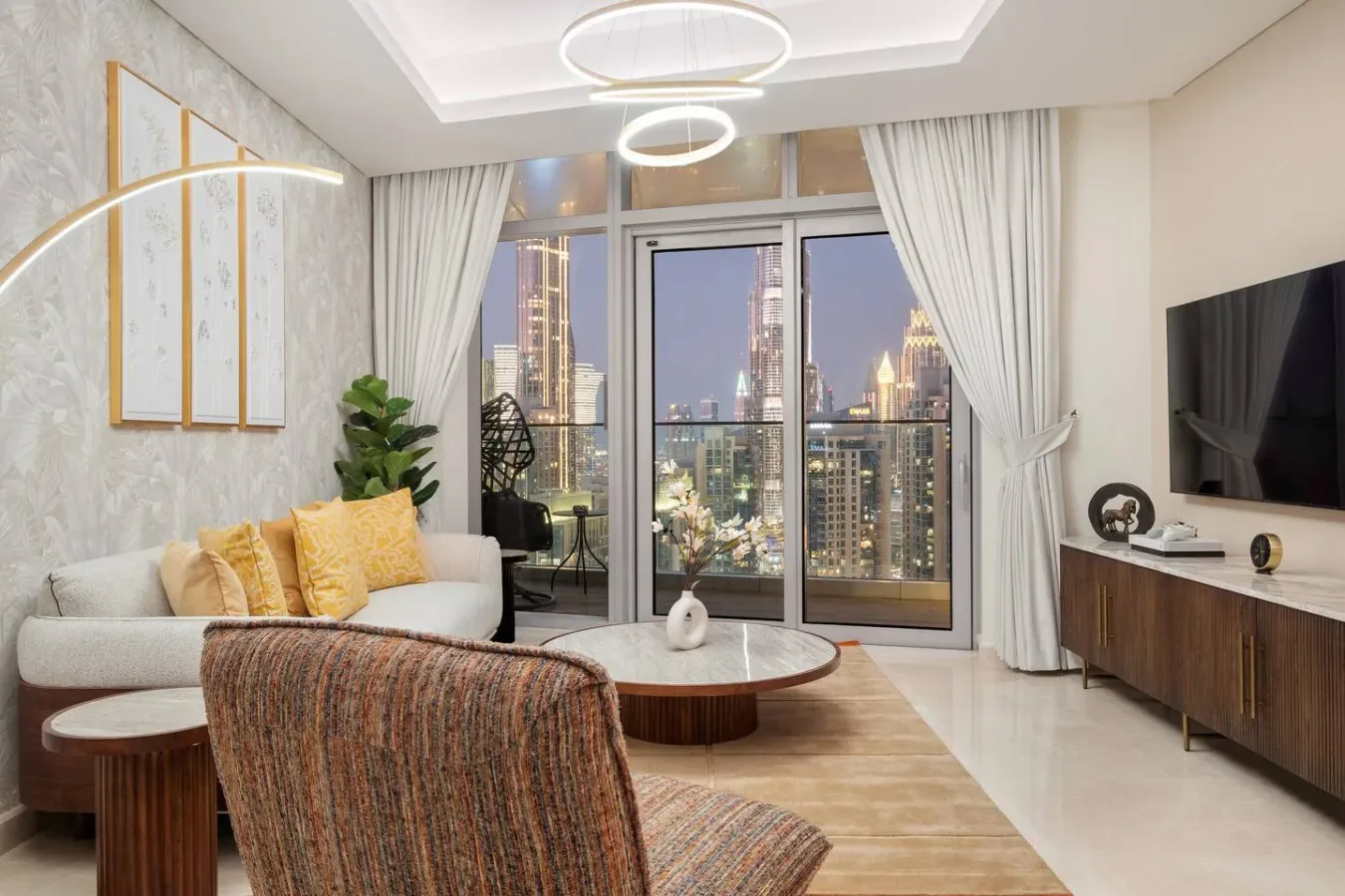 A modern living room has a seating area beside large windows overlooking a city skyline.