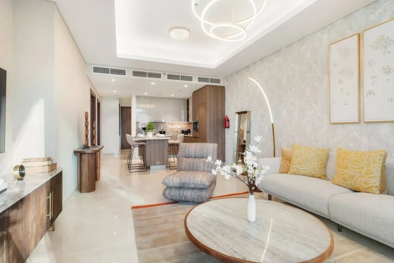 A bright living room with a sofa, lounge chair, and dining area beyond.