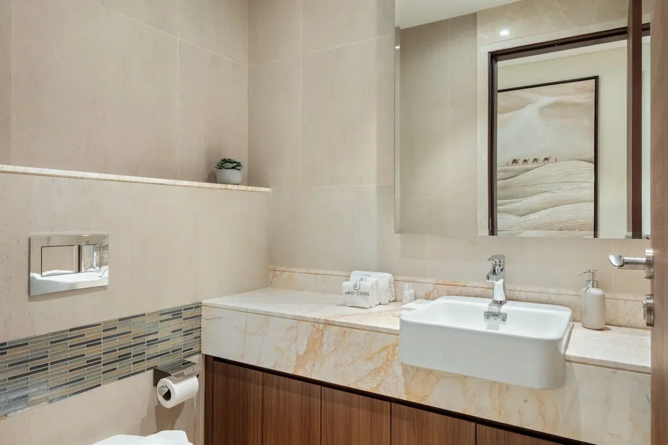 A bathroom vanity with a wide mirror, countertop sink, and tiled walls.