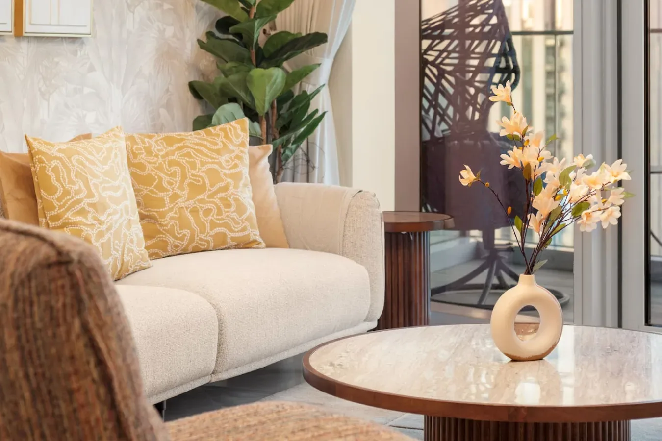 A bright living room with a cream sofa and a round coffee table.