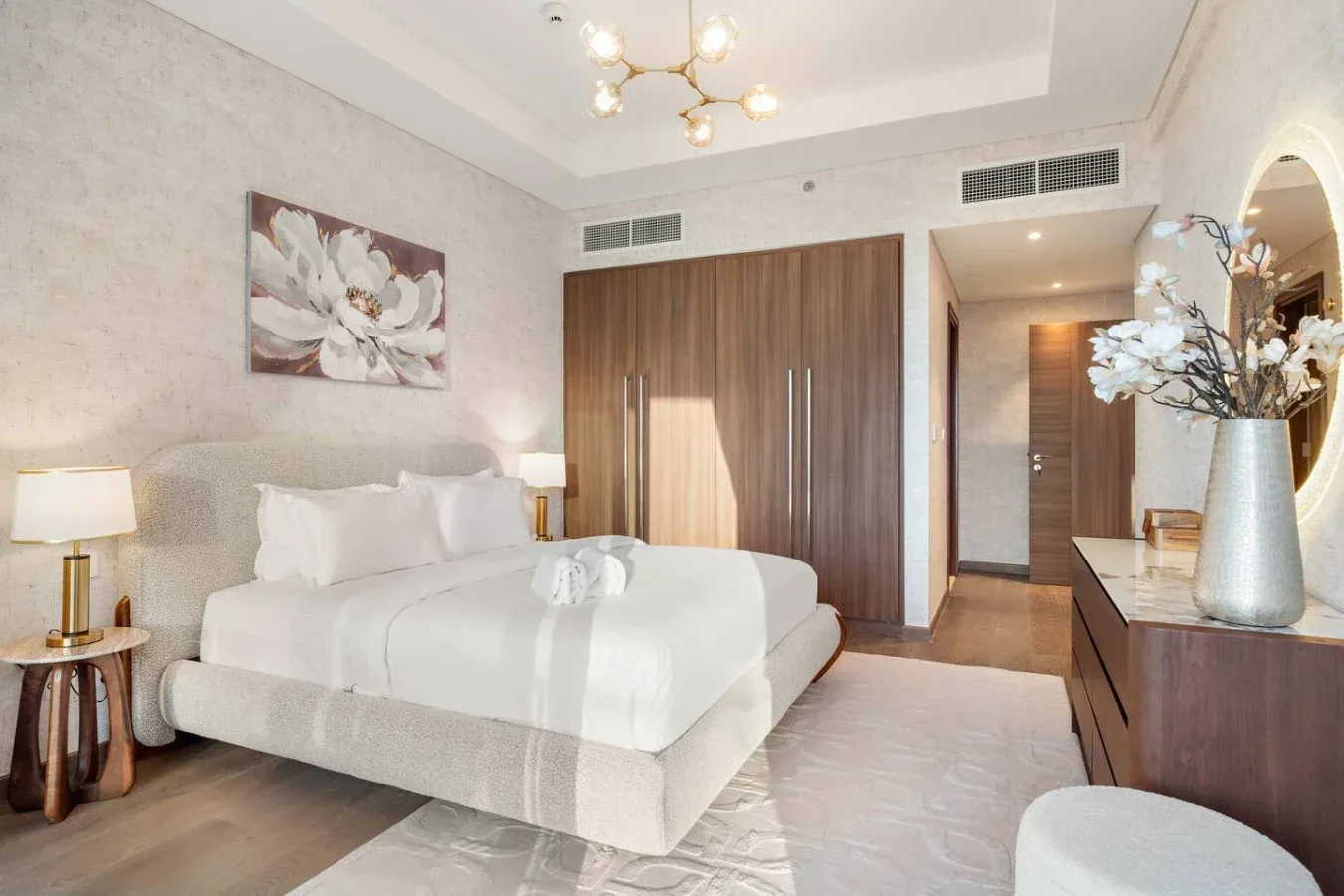 A bedroom with a neatly made bed and a wood-finish wardrobe.