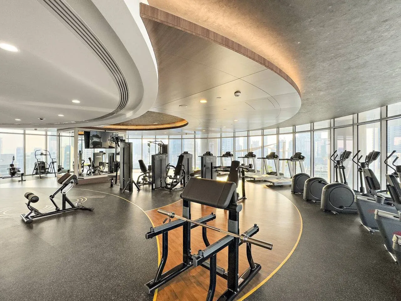 A gym with exercise machines and large windows.