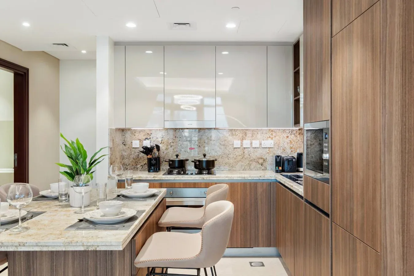 A modern kitchen with a stone island, built-in appliances, and bar seating.