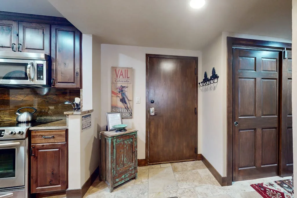 Una entrada interior con una puerta de madera junto a una cocina compacta.