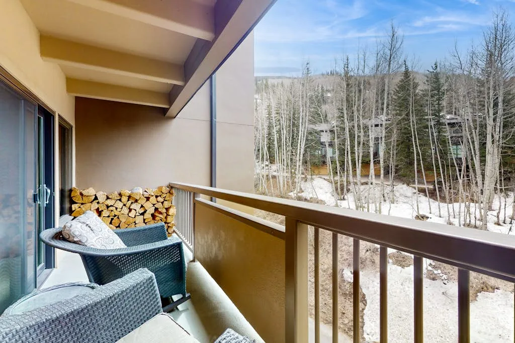 A covered balcony with seating overlooks leafless trees and patches of snow.