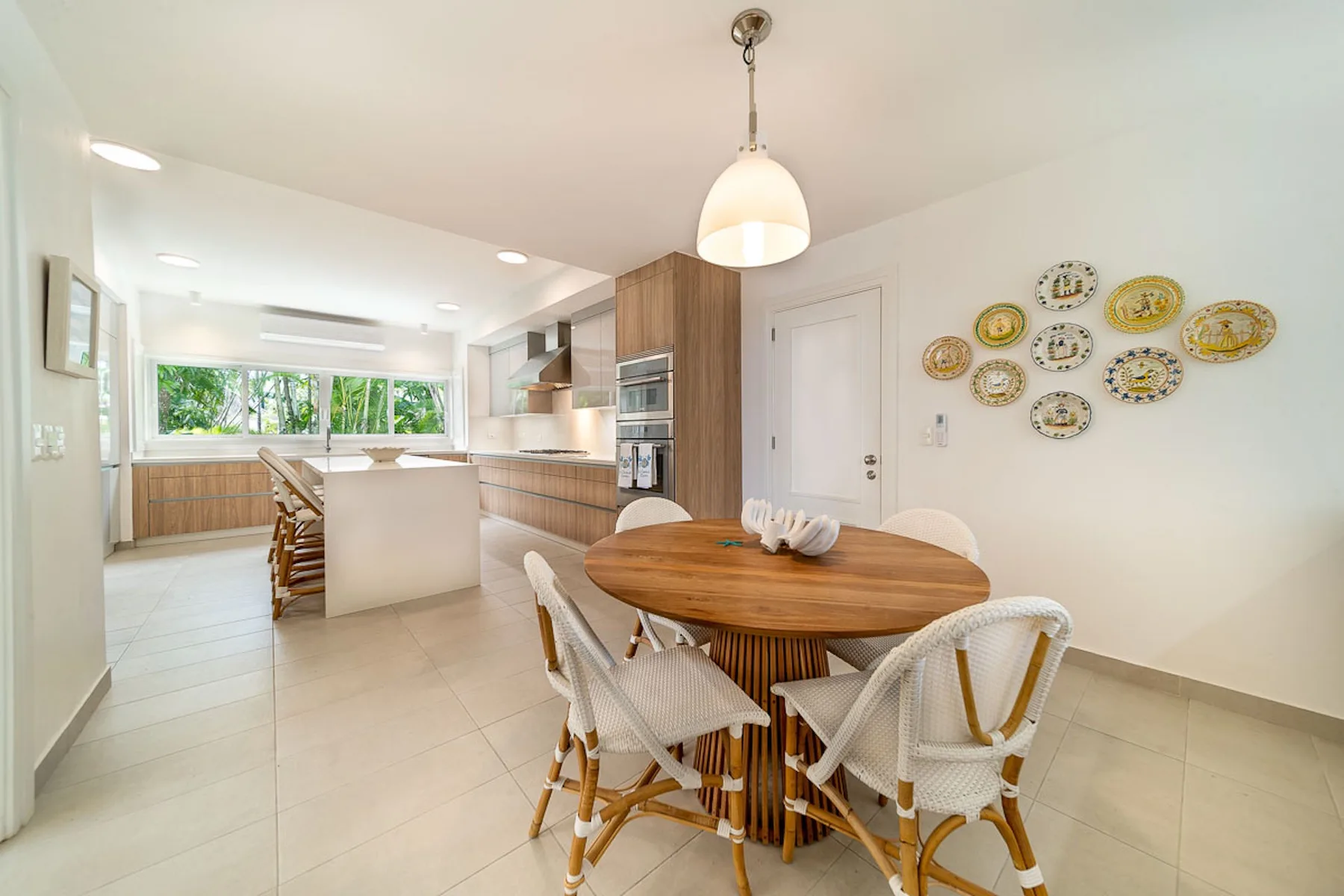 Una cocina abierta con comedor, mesa de madera y asientos tejidos.