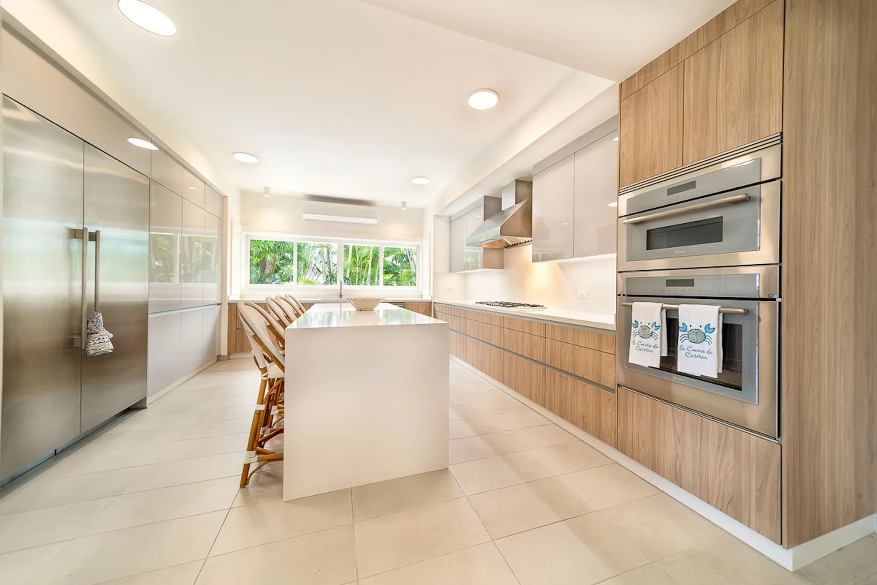 Una cocina luminosa con isla central, gabinetes de madera y electrodomésticos de acero inoxidable.