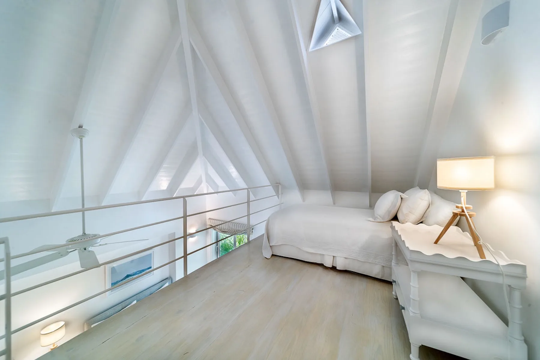 Una luminosa zona de descanso tipo loft con cama y lámpara junto a una pared inclinada.