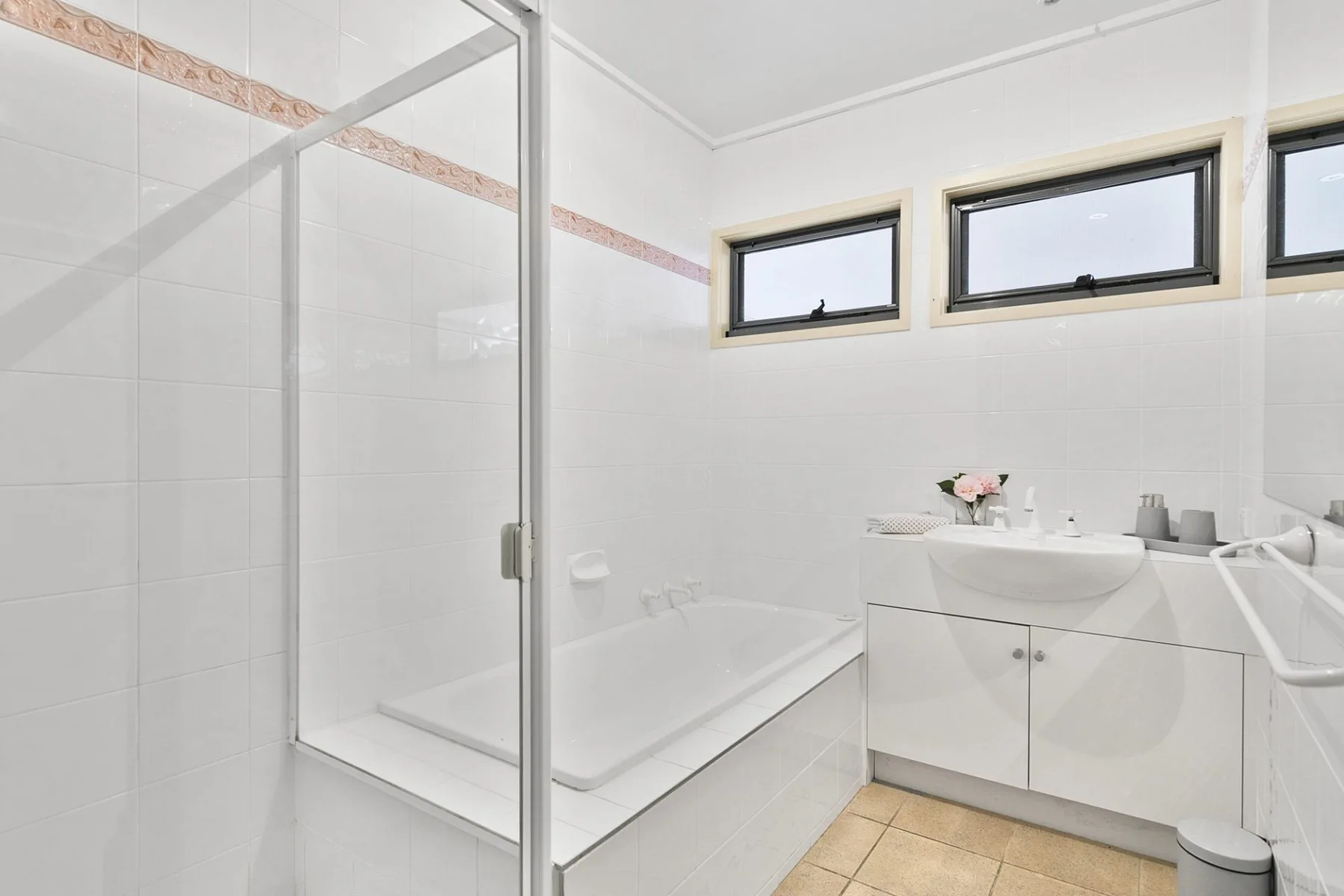 Un baño luminoso con ducha de vidrio y un lavabo con mueble.