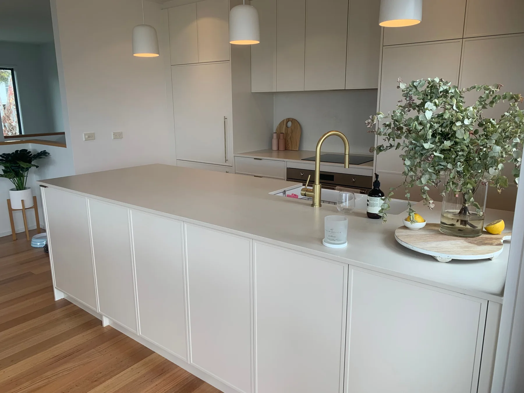 Una cocina luminosa con una isla larga, fregadero y lámparas colgantes.