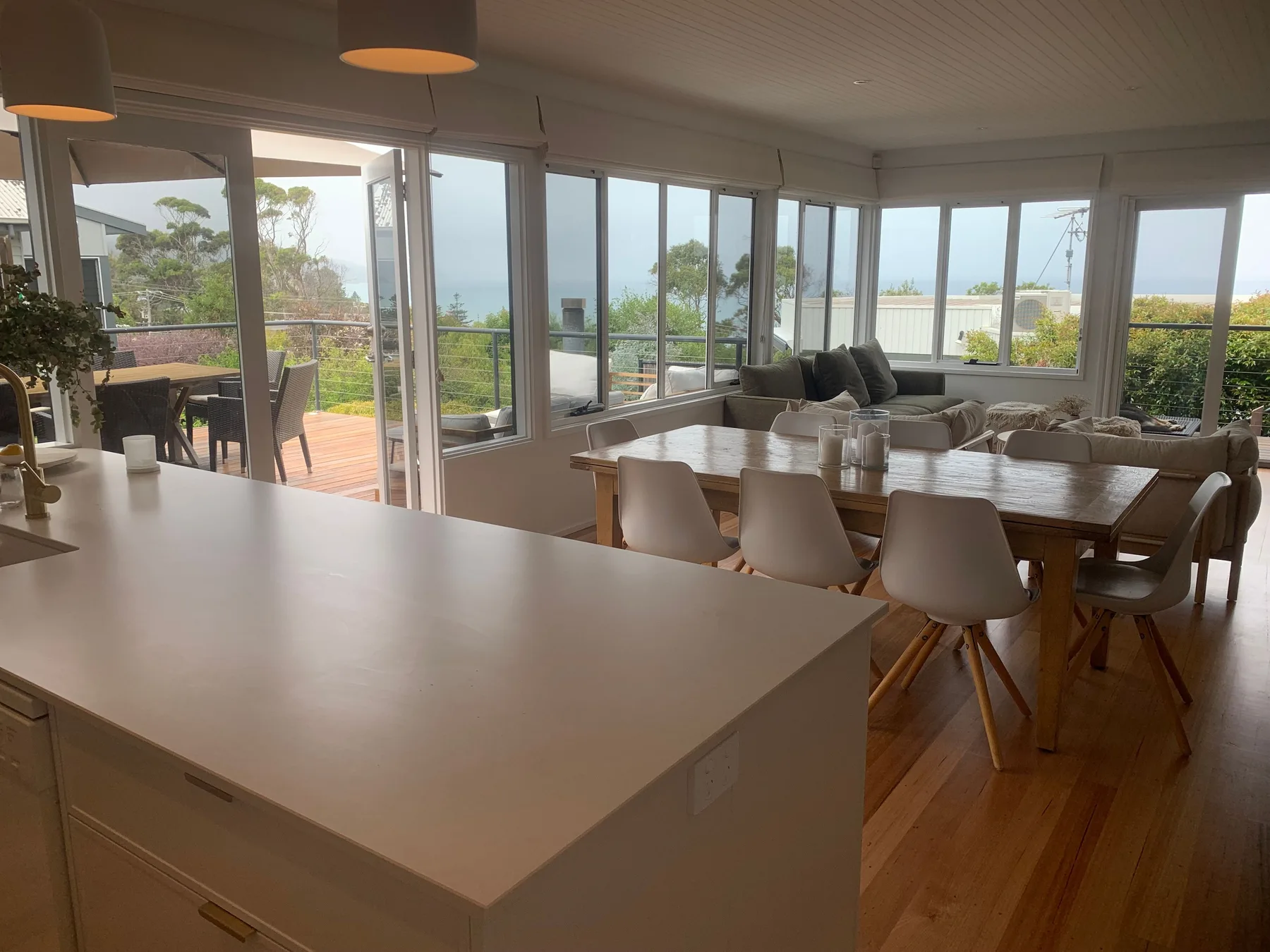 Un comedor abierto y luminoso con sala de estar tiene amplios ventanales con vistas a la costa.