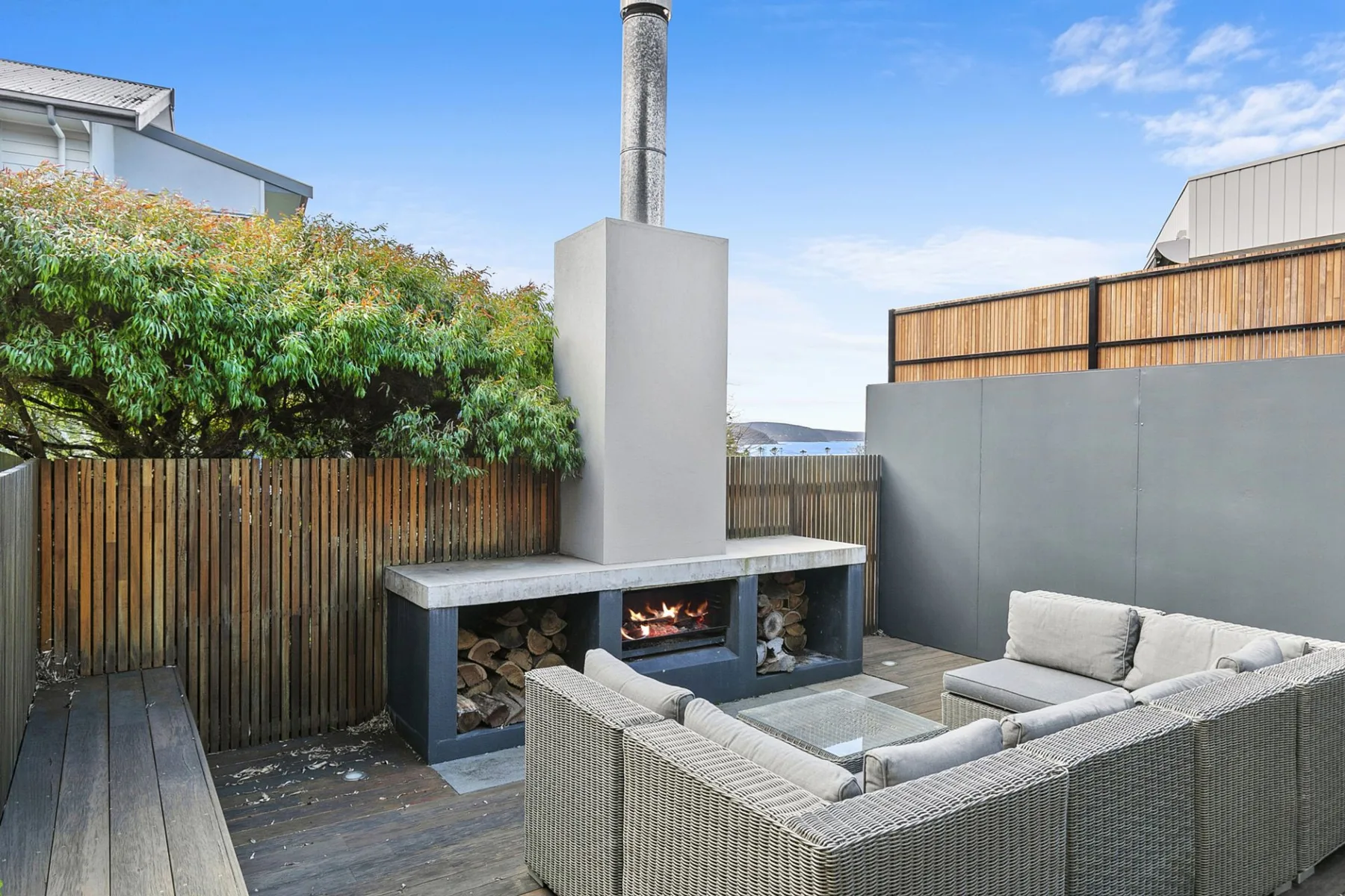 Una zona de estar en un patio exterior con chimenea y paneles de madera.
