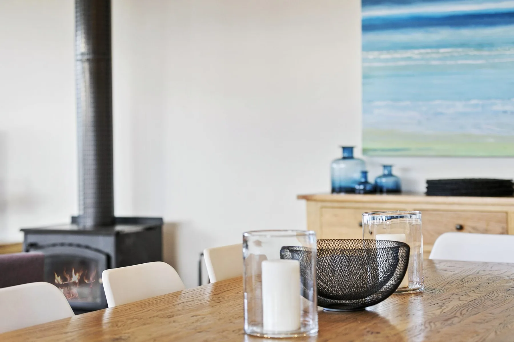 Una mesa de comedor y asientos están junto a una estufa en una habitación luminosa.
