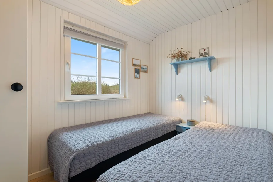 Un dormitorio con dos camas y una ventana con vistas a la vegetación.