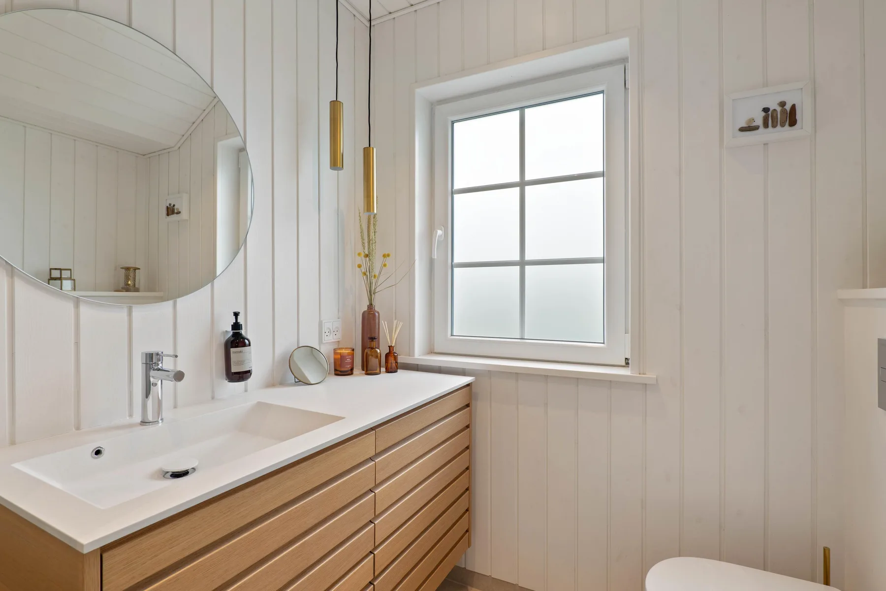 Un baño luminoso con lavabo, espejo grande y ventana.