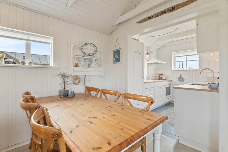 Un comedor luminoso con una mesa de madera junto a una cocina abierta.