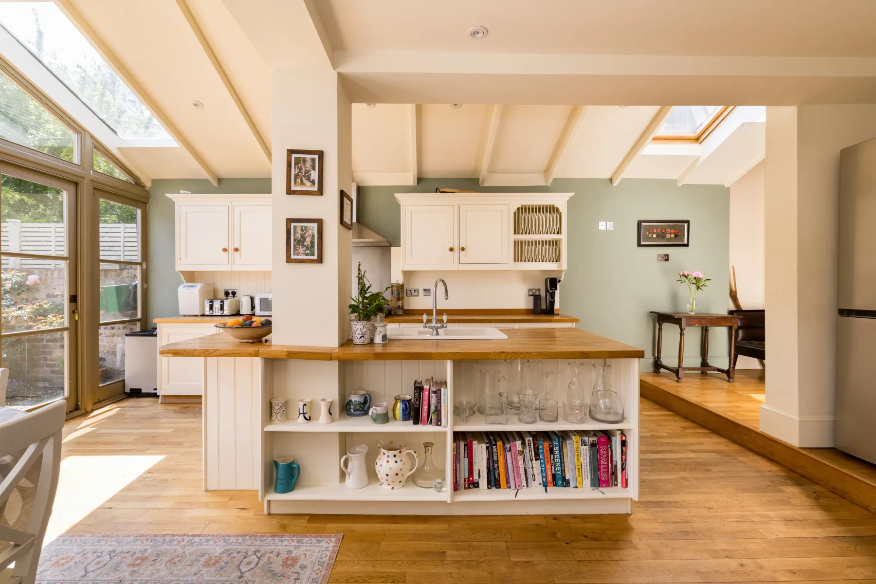 Una cocina luminosa con una isla de madera y grandes ventanas inclinadas.