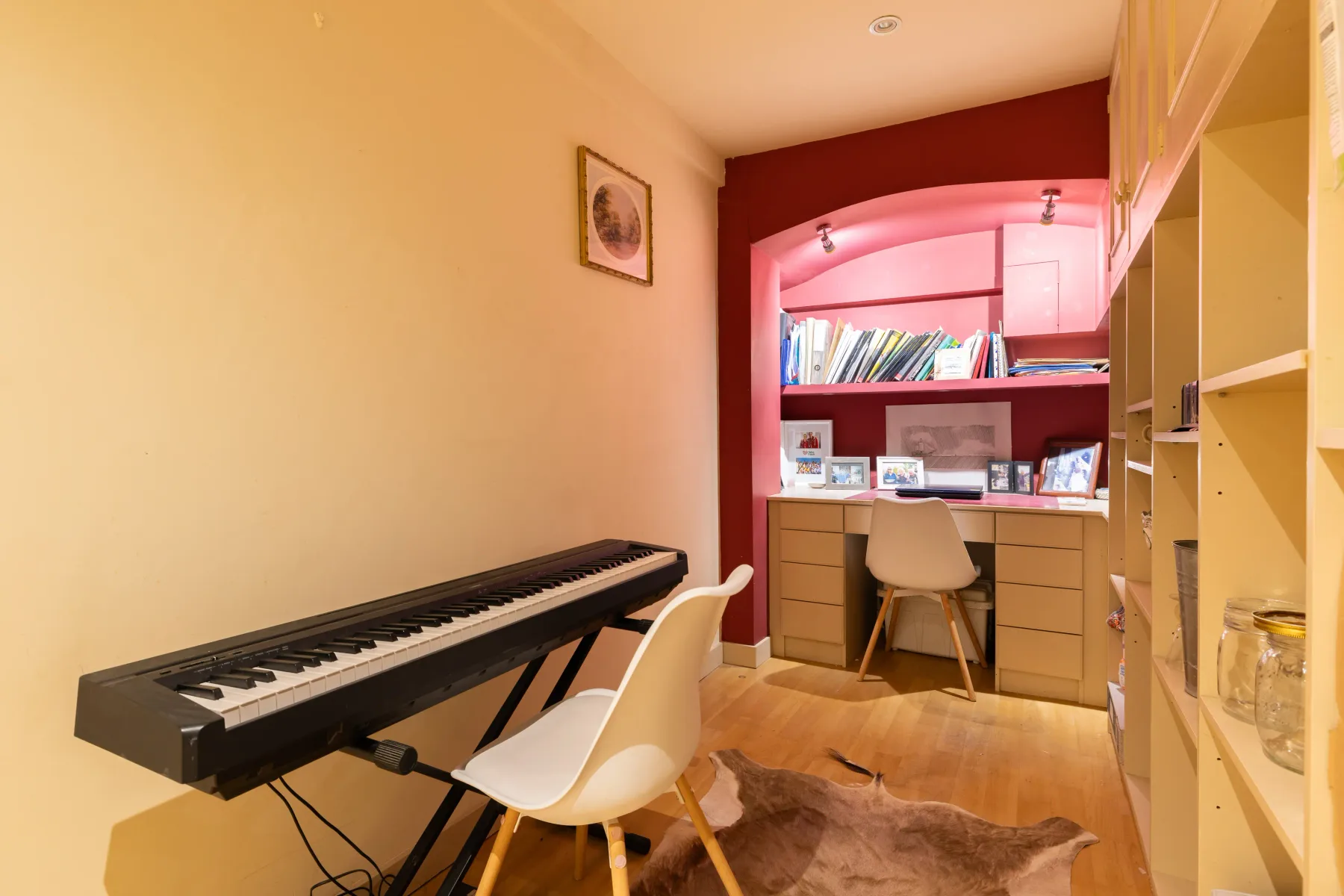 Sala de música y estudio con un teclado, escritorio y estanterías empotradas.