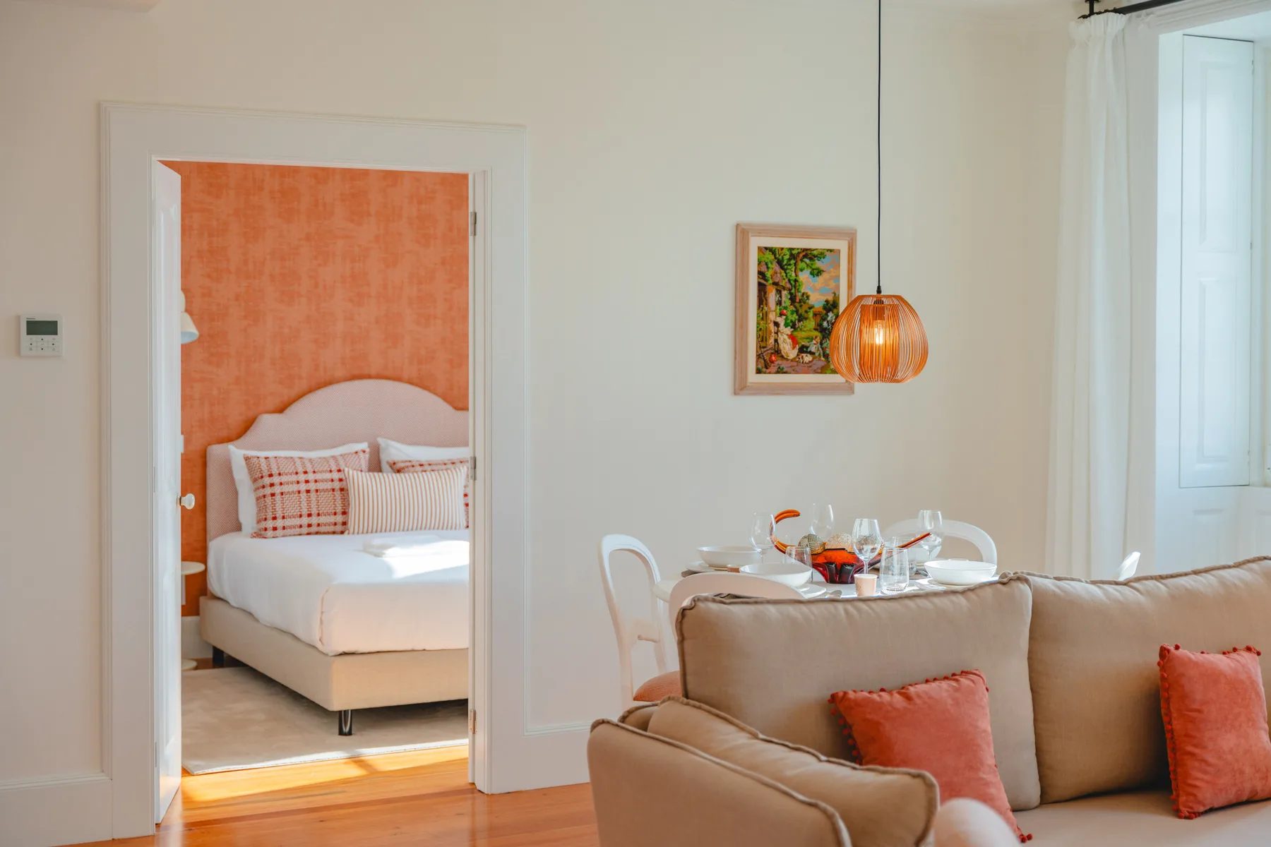 A bright living room with seating and a view into a bedroom.
