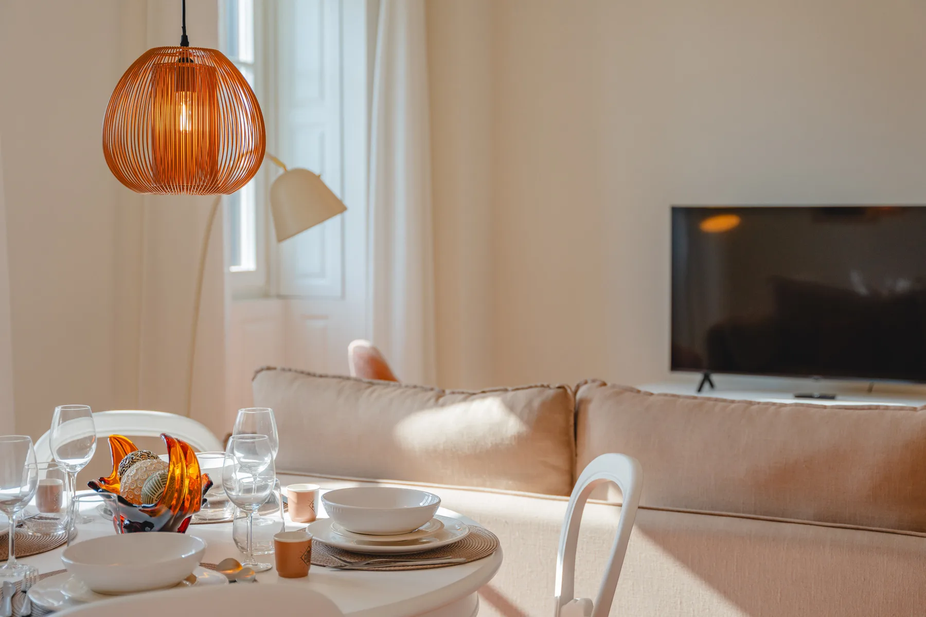 Una sala de estar y comedor con la mesa puesta junto a un sofá y un televisor.