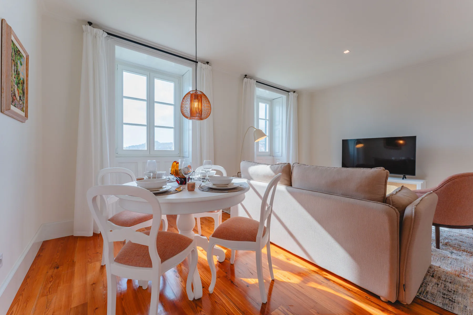 A bright living and dining area with a set table beside the windows.