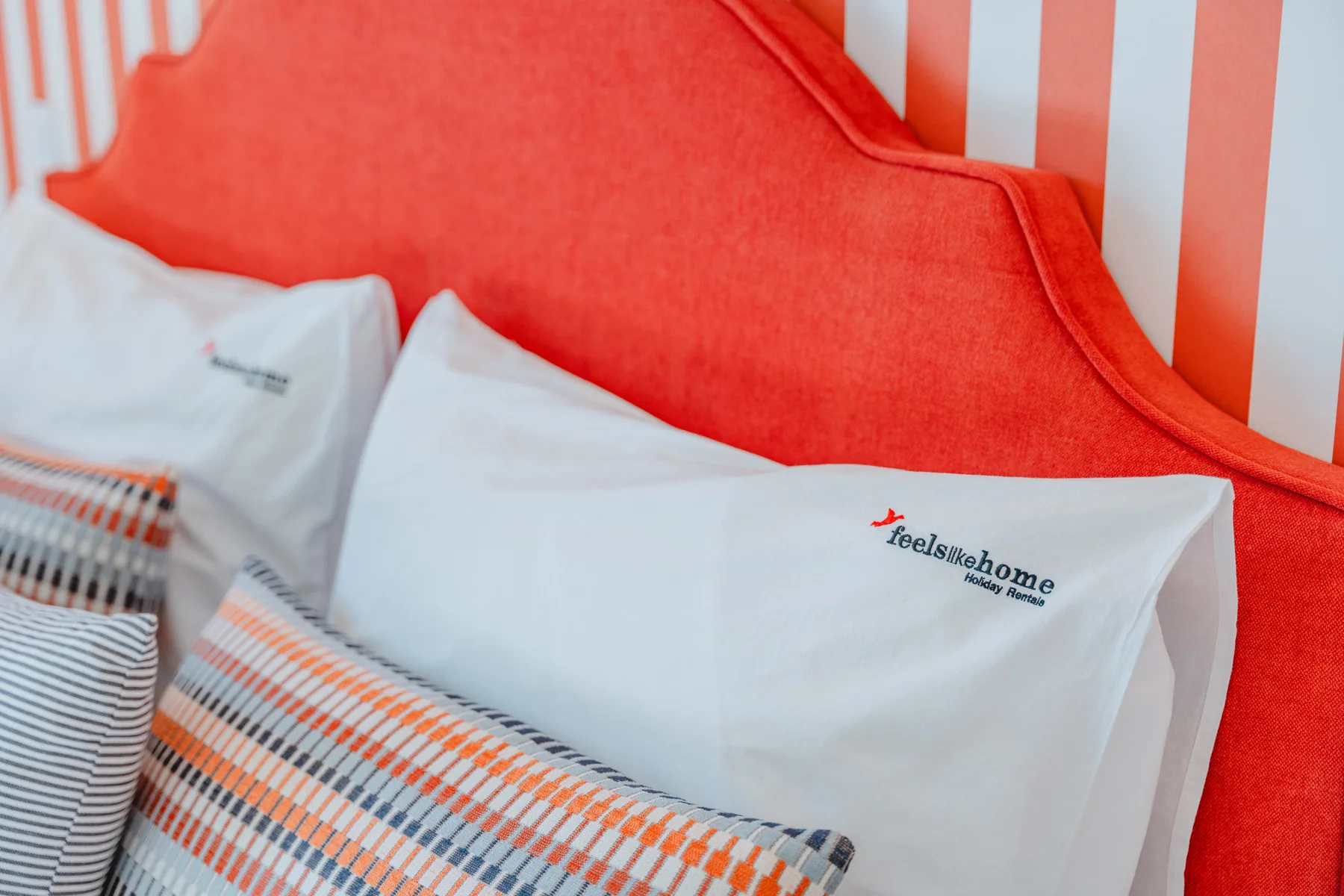 A bedroom with white pillows against a bright red headboard.
