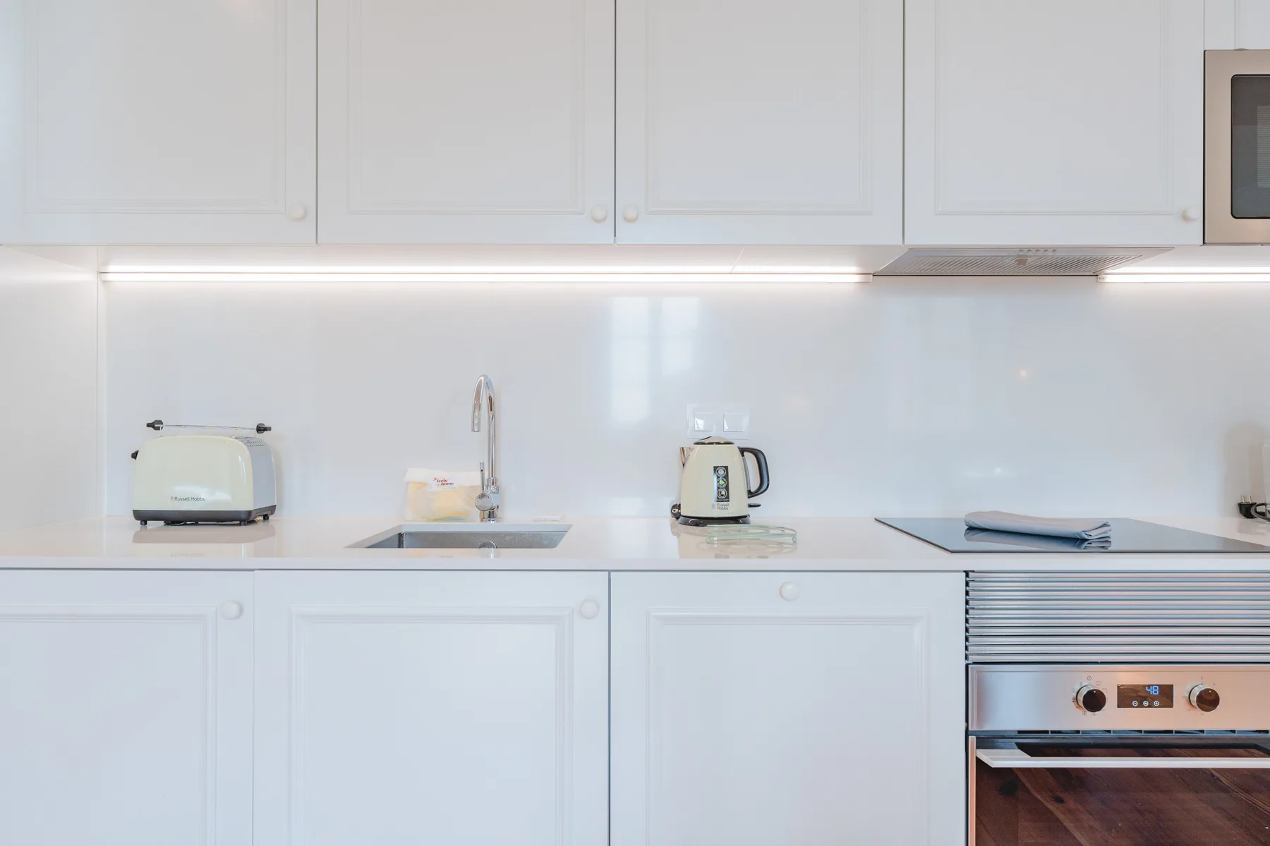 A bright kitchen with white cabinets, a countertop, and built-in appliances.