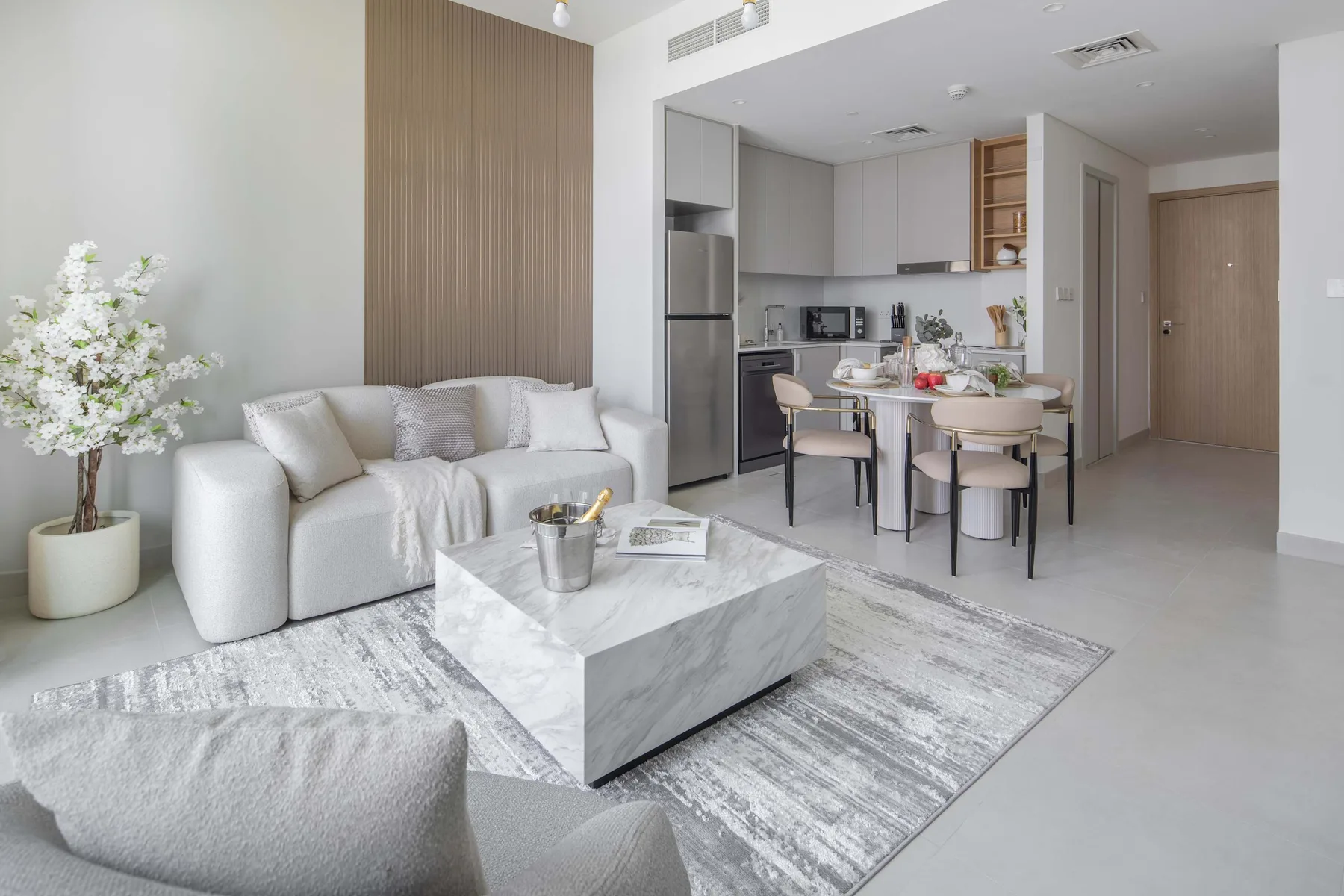 Una luminosa sala de estar y comedor con sofá, mesa de centro y cocina abierta.